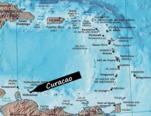A map of the Caribbean Sea highlights Curacao with a bold black arrow pointing to the island near Willemstad, off Venezuela's coast. Surrounding islands such as Puerto Rico, Aruba, and Trinidad are clearly labeled.