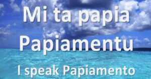 Text reads Mi ta papia Papiamentu. I speak Papiamento over a bright blue ocean near Curacao, under a partly cloudy sky with sunlight reflecting off the water. The scene looks tropical and inviting.