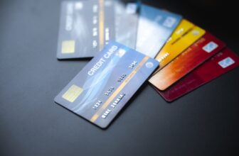 Un primer plano de cinco coloridas tarjetas de crédito y débito desplegadas sobre una superficie oscura, con los detalles de la tarjeta parcialmente visibles y el foco en la tarjeta de débito azul del anverso, evocando una vibrante paleta inspirada en Curaçao.